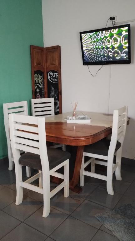 een houten tafel met vier witte stoelen eromheen bij Linaje Hospedaje in Colón