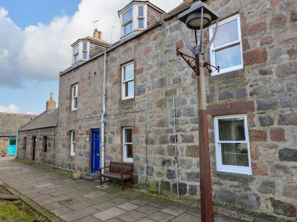 an old stone building with a street light next to it at Footdee Cottage in Aberdeen
