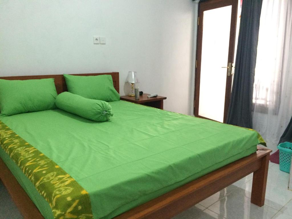 a bedroom with a green bed with a window at Linggy Homestay in Nusa Lembongan