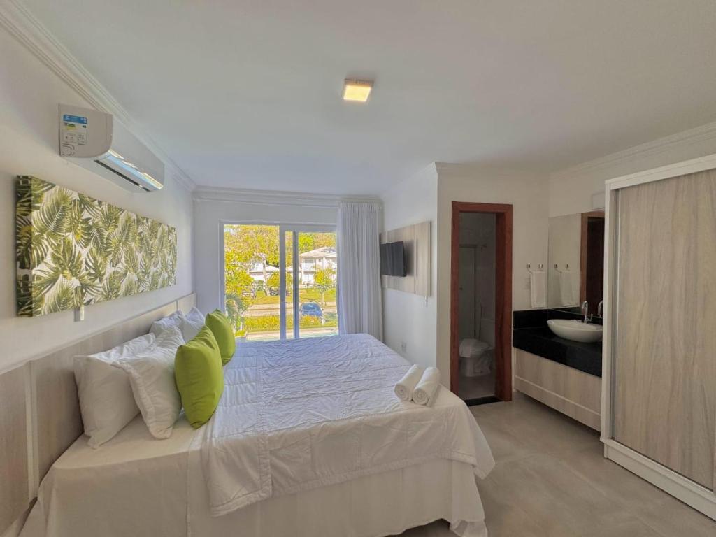 ein Schlafzimmer mit einem großen weißen Bett mit grünen Kissen in der Unterkunft Apto para temporada em Arraial D'ajuda in Porto Seguro