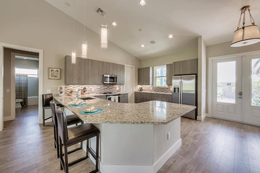 Una cocina con una gran isla con taburetes de bar. en Pool Home with Beach Access - Southern Comfort - Roelens, en Fort Myers Beach
