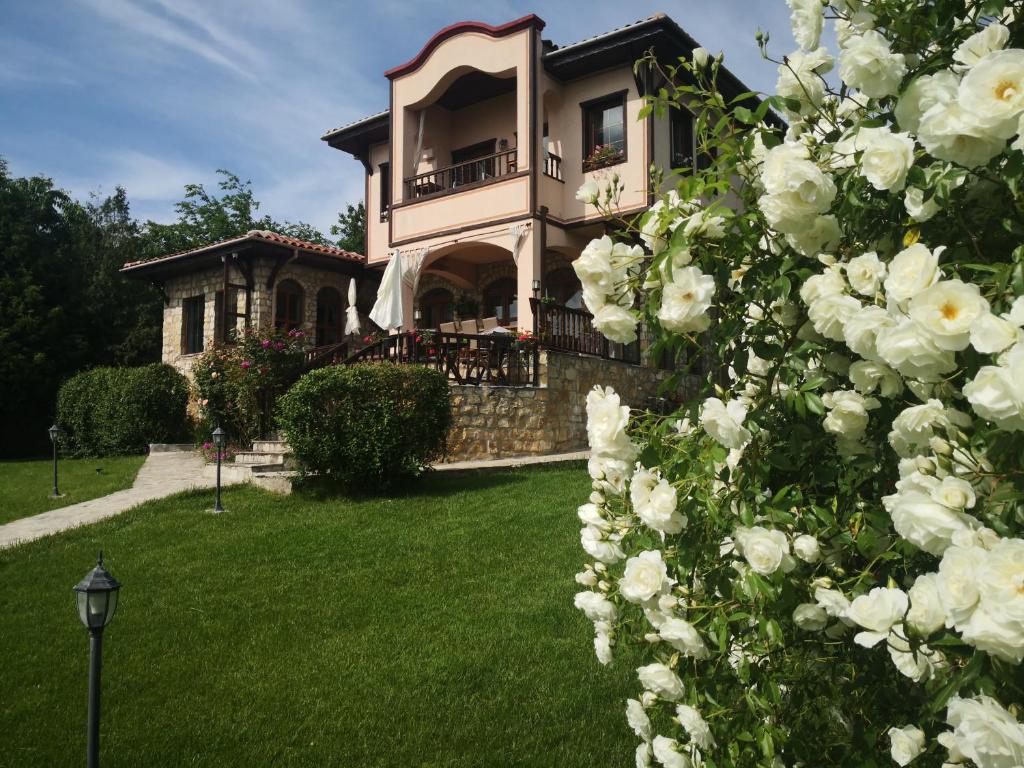 une maison avec des roses blanches devant elle dans l'établissement къща за гости villa Jurta, à Avren