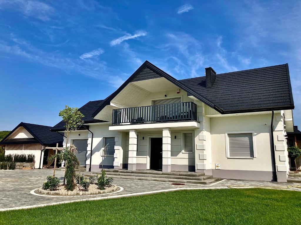 a white house with a black roof at Apartamenty Noclegowe U Bartosza in Odrzechowa