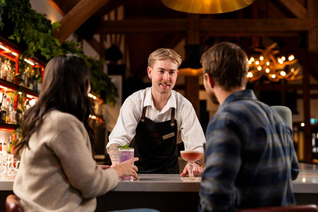 a man standing at a bar talking to two people at Buffalo Mountain Lodge in Banff