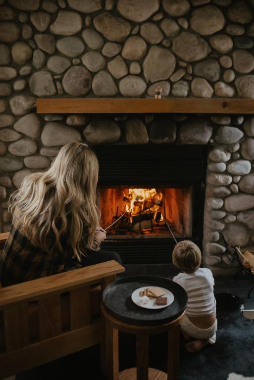 a woman and a child sitting in front of a fireplace at Buffalo Mountain Lodge in Banff