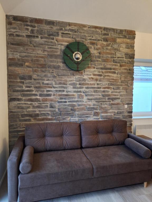 a brown couch against a brick wall with a clock at Walhalla in Xanten