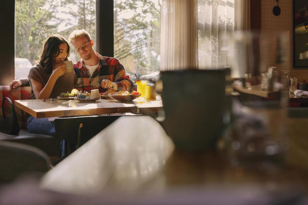 a man and woman sitting at a table eating food at Buffalo Mountain Lodge in Banff