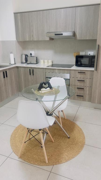 a kitchen with a glass table and two white chairs at Nala Realty at The Aura in Sandton