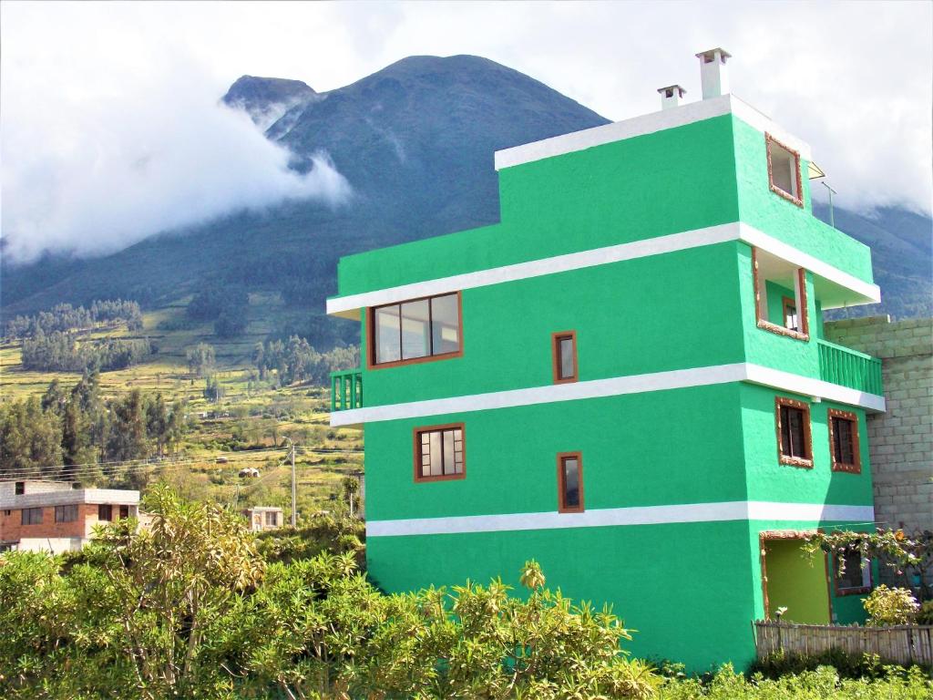 a green building with a mountain in the background at Green House Araque Inn in Otavalo