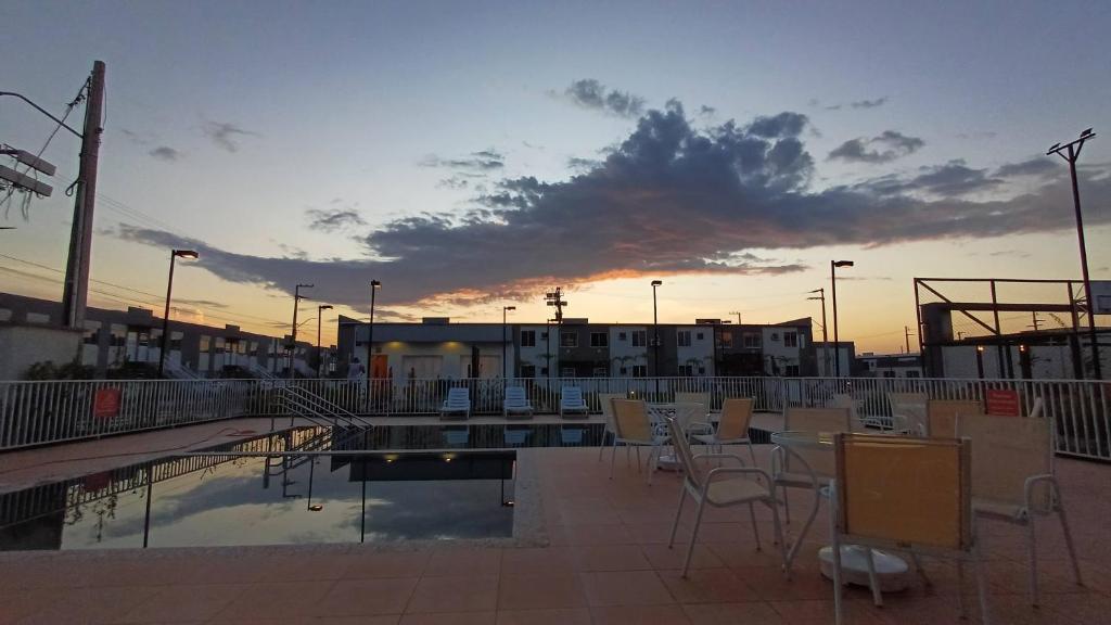 eine Terrasse mit Stühlen und einem Tisch mit Blick auf den Sonnenuntergang im Hintergrund in der Unterkunft Vivendas do Rio 1 in Ananindeua