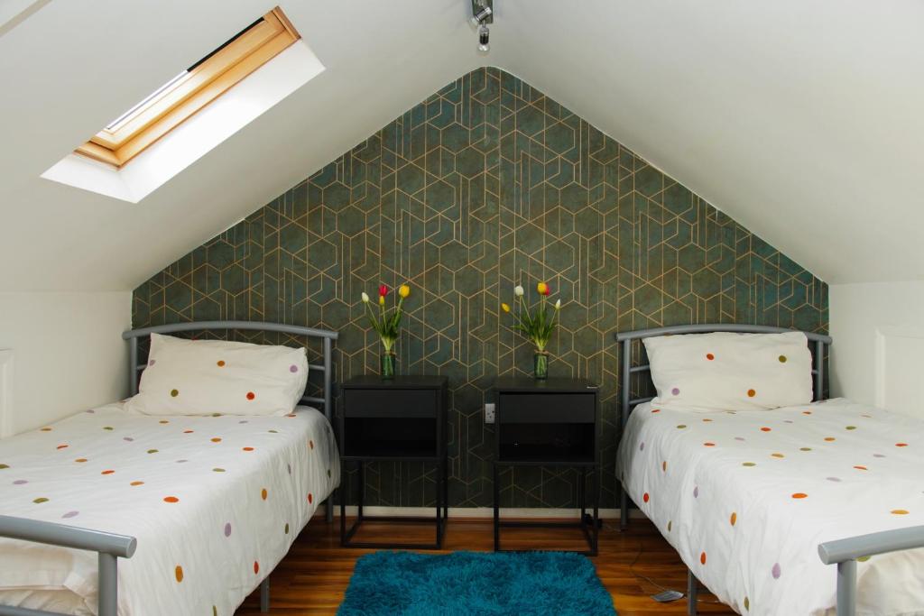 2 Betten in einem Schlafzimmer im Dachgeschoss mit grüner Wand in der Unterkunft House near Cardiff City Centre in Cardiff