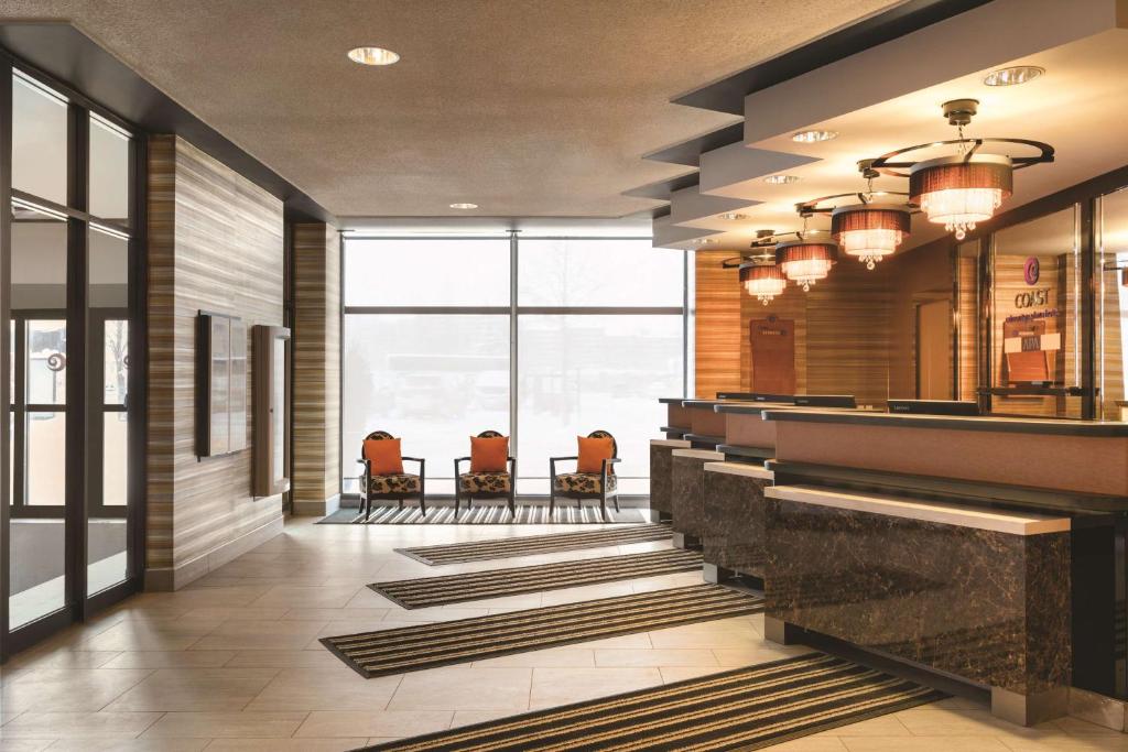 a lobby with a bar with orange chairs and windows at Coast Edmonton Plaza Hotel by APA in Edmonton