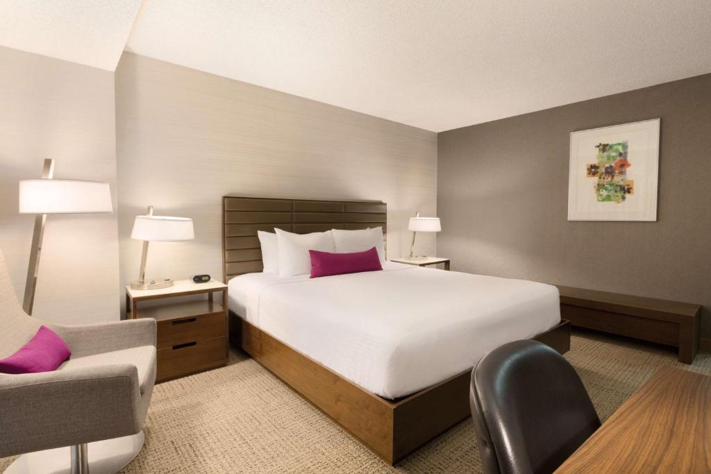 a hotel room with a large bed and a chair at Coast Edmonton Plaza Hotel by APA in Edmonton