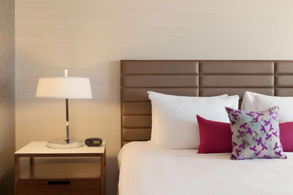 a bedroom with a bed with a lamp and pillows at Coast Edmonton Plaza Hotel by APA in Edmonton