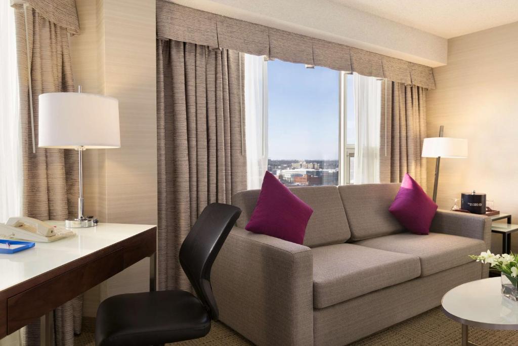 a living room with a couch and a desk and a window at Coast Edmonton Plaza Hotel by APA in Edmonton
