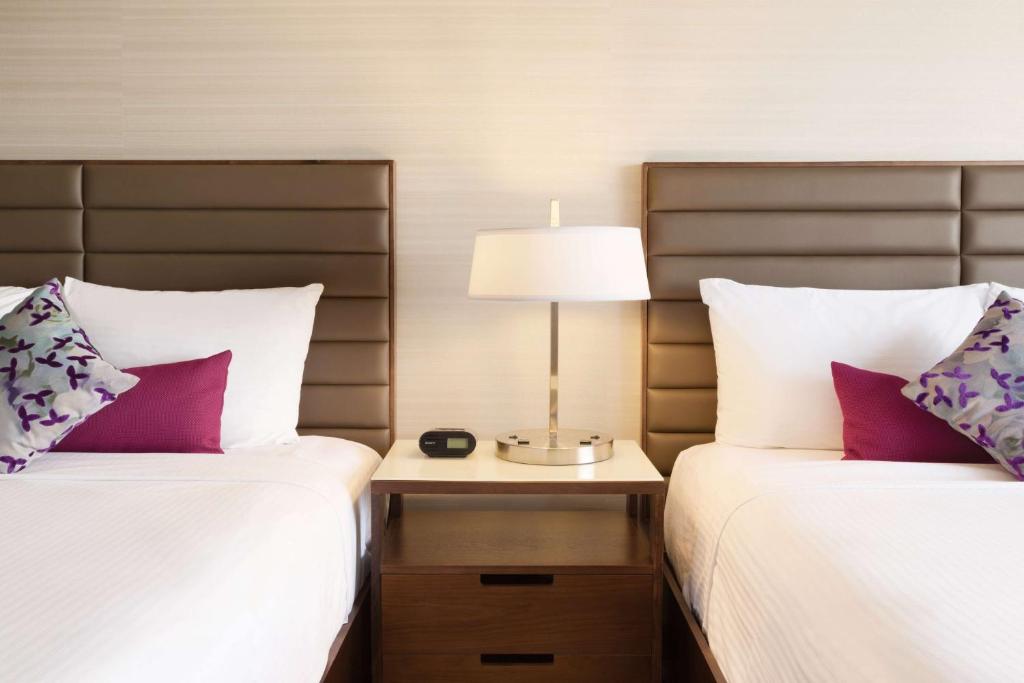 a bedroom with two beds and a lamp on a night stand at Coast Edmonton Plaza Hotel by APA in Edmonton