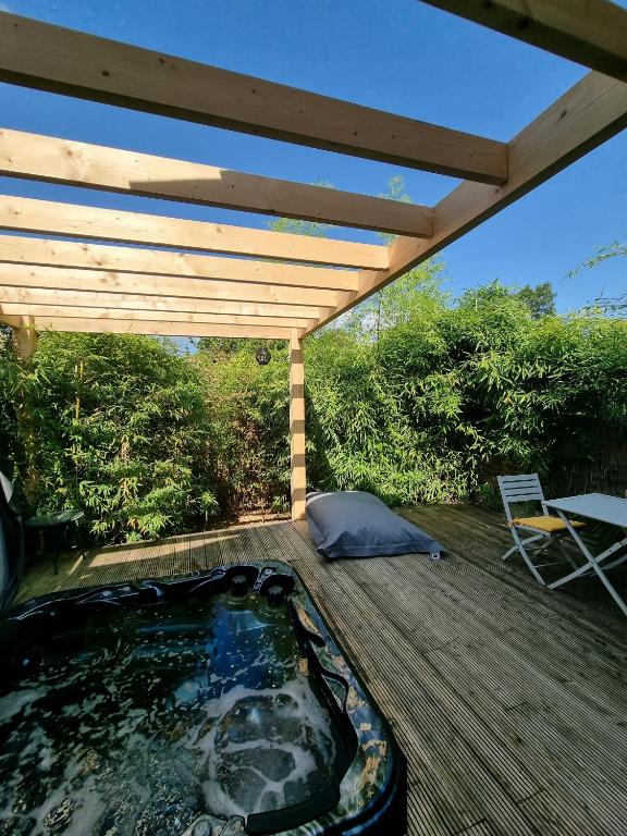 un bain à remous sur une terrasse avec un toit en bois dans l'établissement L ABRI spa et détente, à Liergues