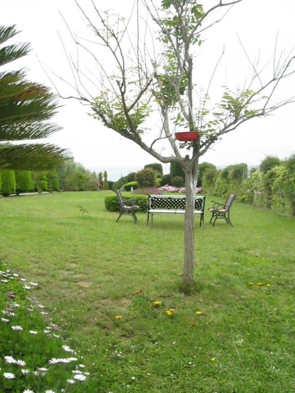 a park with two benches and a bird feeder on a tree at Ground beach studio in Nea Potidaea