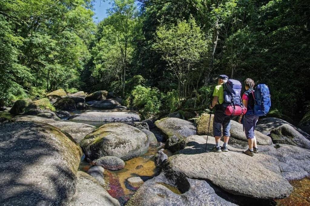 two people with backpacks standing on rocks in a river at Loulo 'dge in Saint-Donan