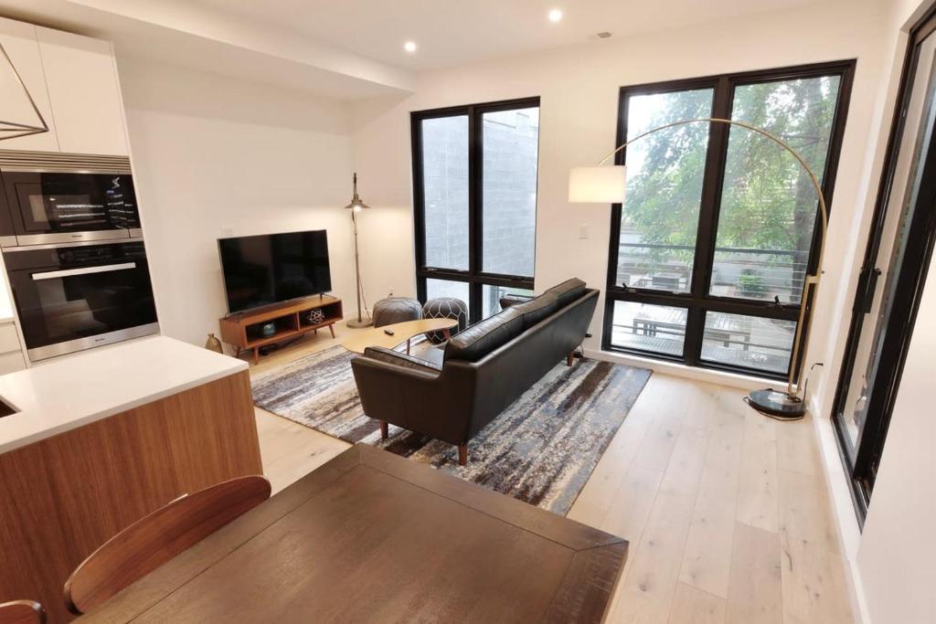 Una sala de estar con un sofá negro y un televisor. en Contemporary Home in Shaw-U Street, en Washington