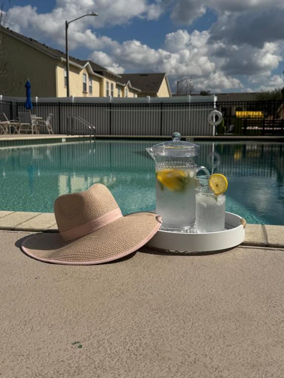 キシミーにあるFamily stay Near Disneyのスイミングプールの横のトレイに飾られた帽子とドリンク