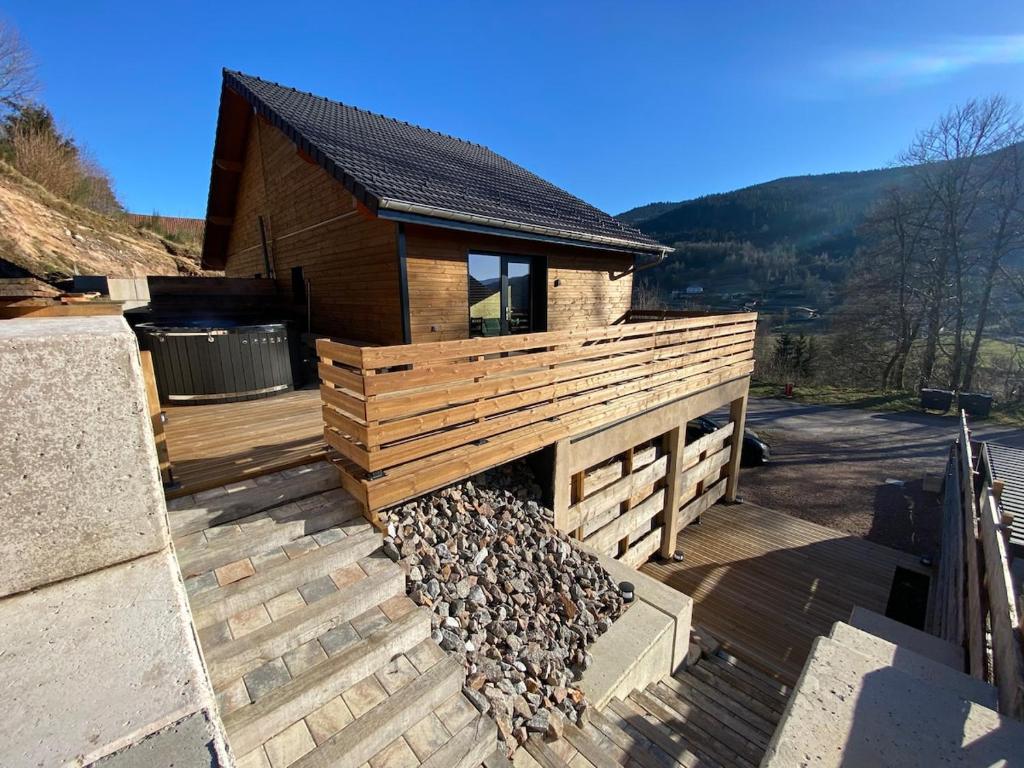 une maison avec une terrasse en bois et un tas de rochers dans l'établissement Chalet iris & Jaccuzi privatif, à Rochesson