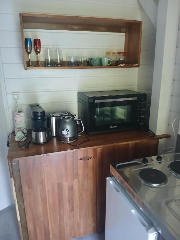 a small kitchen with a microwave and a stove at Bungalow Lolo Moringa in Bouillante