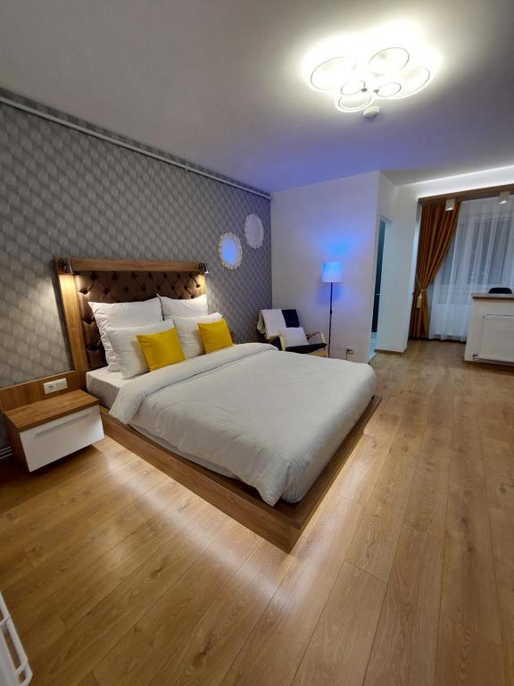 a bedroom with a large white bed with yellow pillows at ONYX - Vision Aparthotel in Braşov