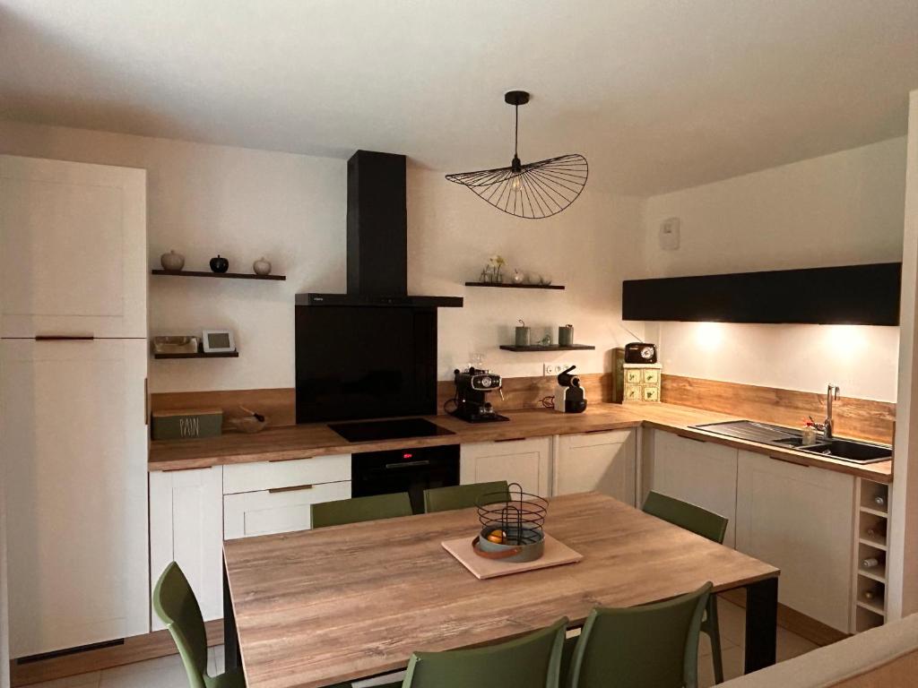 une cuisine avec une table en bois et des chaises vertes dans l'établissement Le petit val, à Pinchefalise