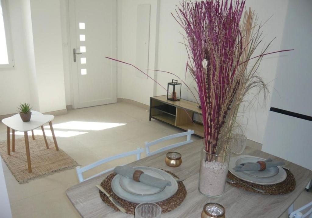 - un salon doté d'une table avec des assiettes et des fleurs dans l'établissement Appartement T2 cosy à colomiers, à Colomiers