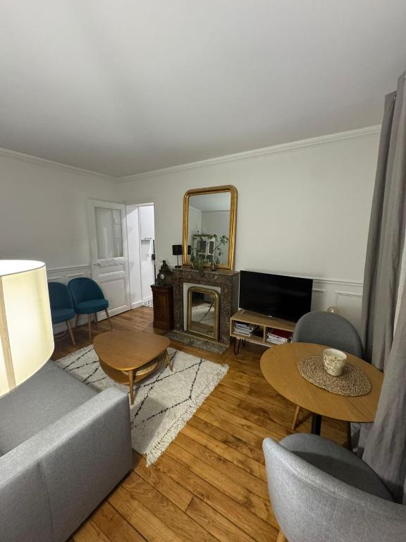 un salon avec un canapé et un miroir dans l'établissement Appartement cosy et calme Pasteur Montparnasse, à Paris