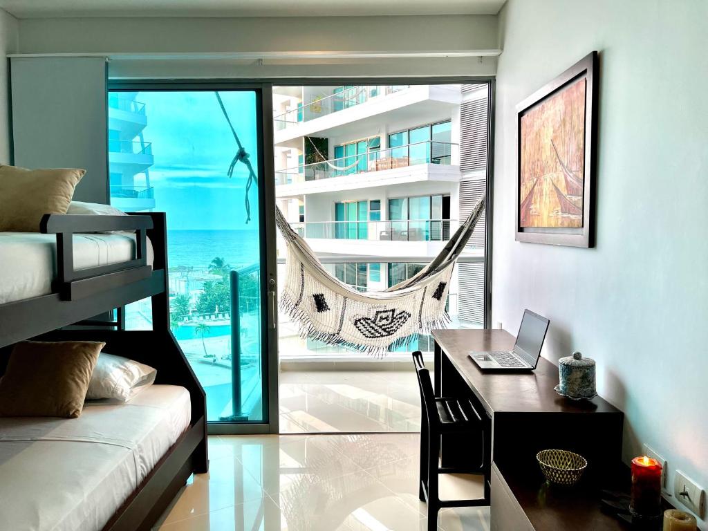 a bedroom with a desk with a laptop and a balcony at Emmaus in Cartagena de Indias