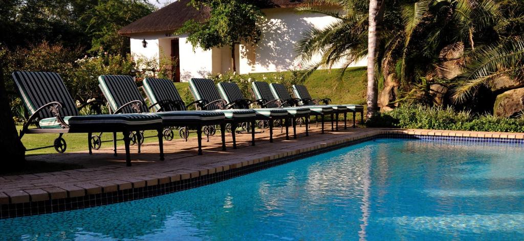 a row of chairs next to a swimming pool at Woodall Country House and Spa in Addo