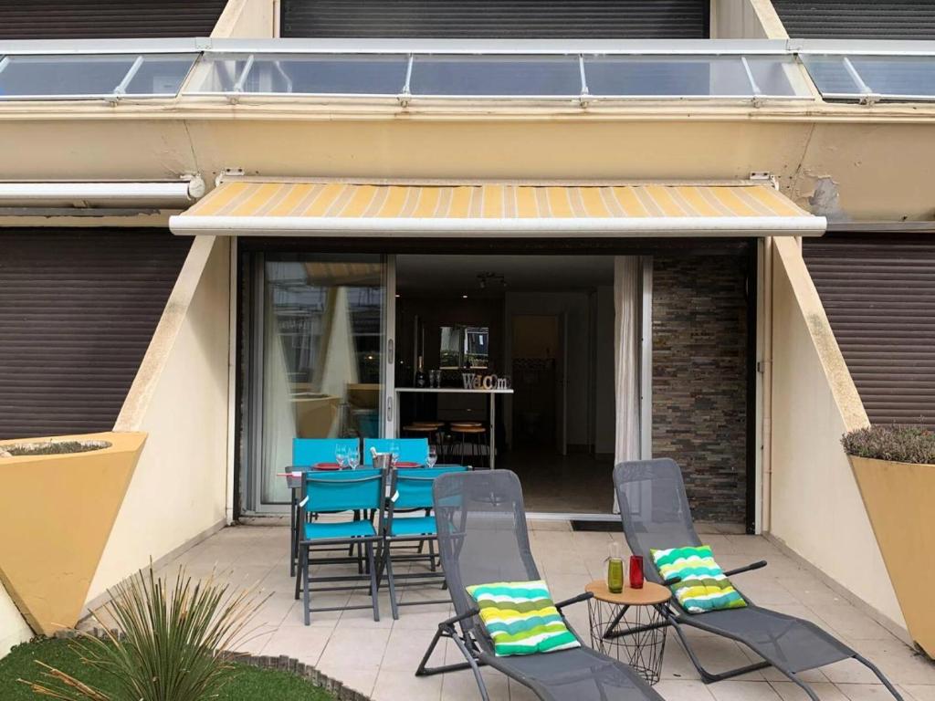 d'une terrasse avec des chaises et une table avec des chaises bleues. dans l'établissement Résidence Héliopolis Bâtiment D - studio 2 Pers. Héliopolis Bât. D MAE-4584, au Cap d'Agde