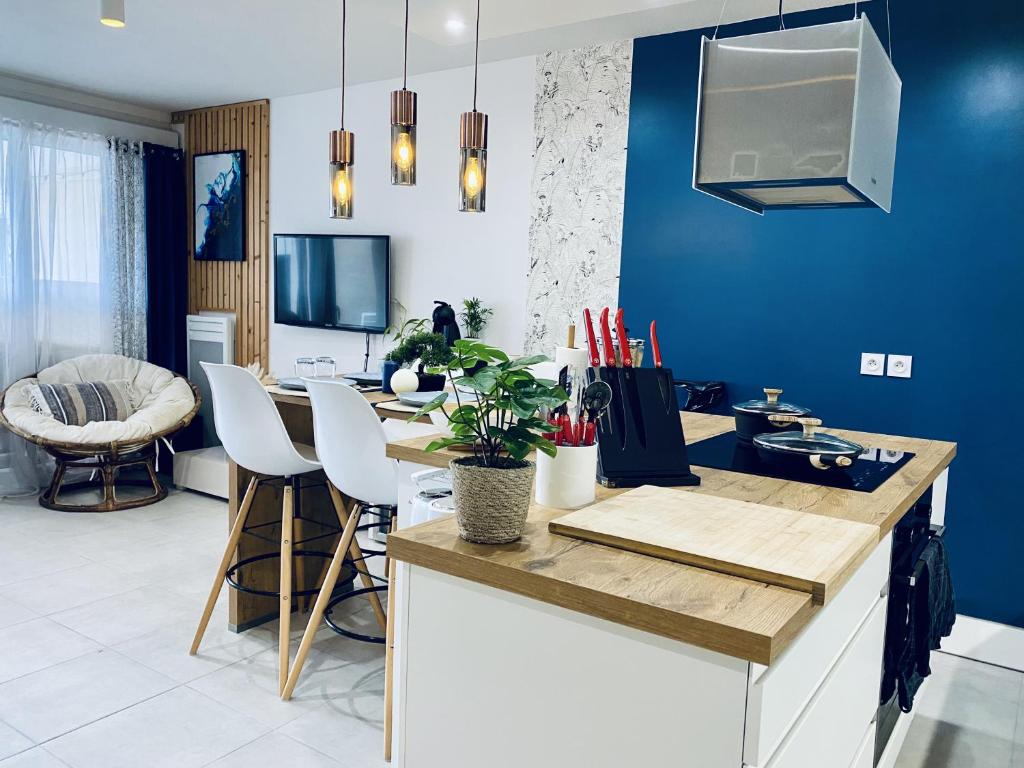 une cuisine aux murs bleus et une table avec des chaises dans l'établissement Cantosia - Appartement T3, Terrasse & Jardin Privatif, à Saint-Brès