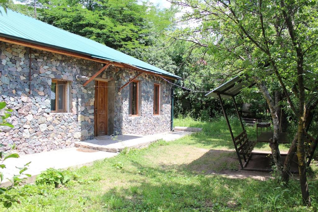 a stone house with a green roof and a swing at GUEST HOUSE IN Dilijan MD GUEST HOUSE in Dilijan