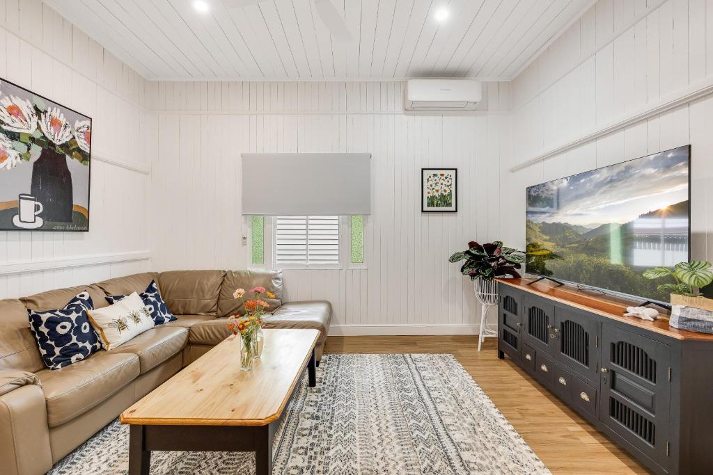 a living room with a couch and a flat screen tv at Bondi Cottage on Queens Park! in Toowoomba
