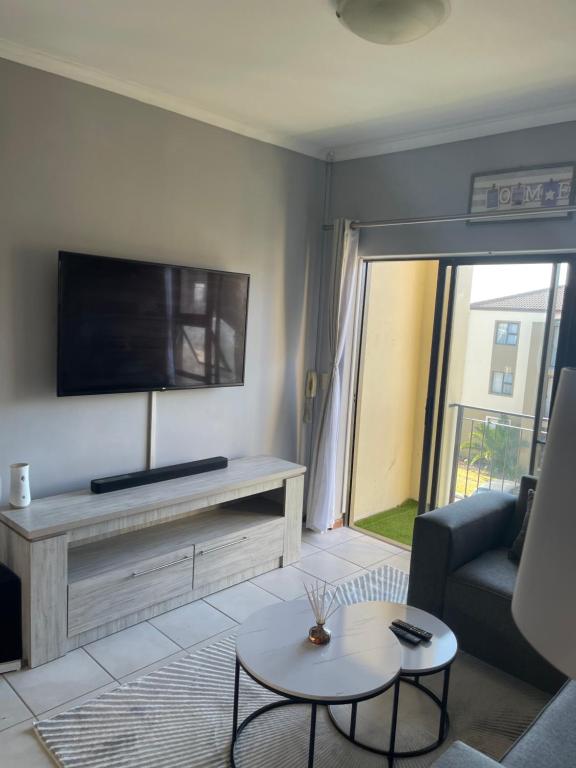 a living room with a tv and a couch and a table at Beautiful 2 bedroom apartment in strand in Somerset West
