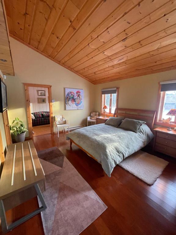 a bedroom with a large bed and a wooden ceiling at Entre Pierre et Bois, couette et café in Lac-Superieur