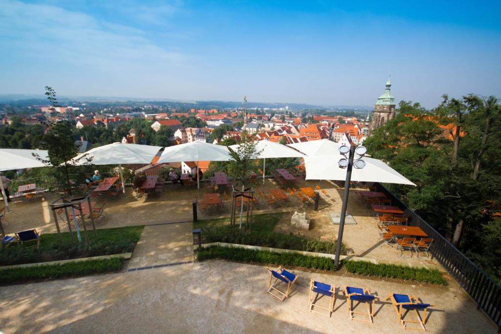 einen Balkon mit Tischen, Stühlen und Sonnenschirmen in der Unterkunft Schloß Sonnenstein in Pirna