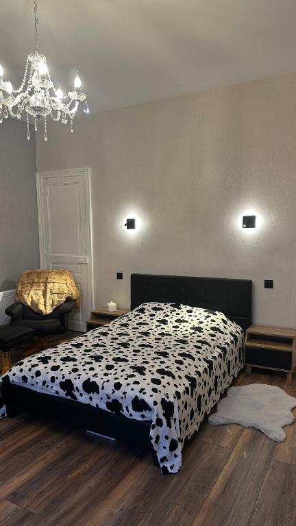 - une chambre avec un lit noir et blanc et un lustre dans l'établissement Appartement JOANNA, à Vittel