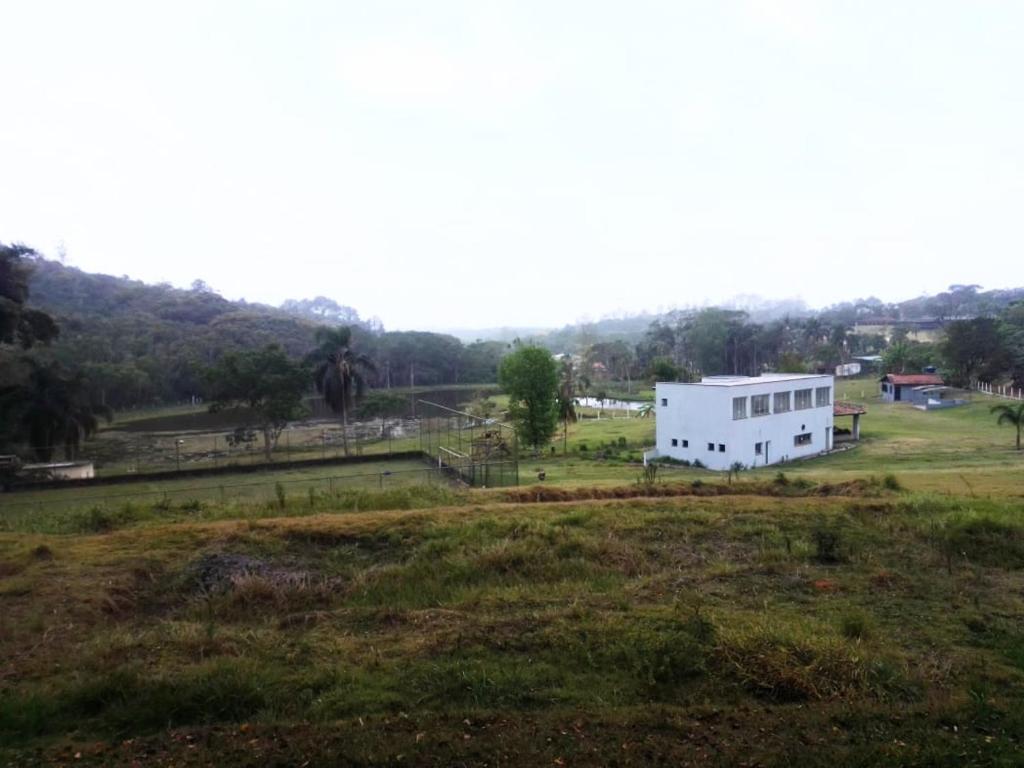 a white building on a grassy field in a field at Pesqueiro ABUX in Mogi das Cruzes