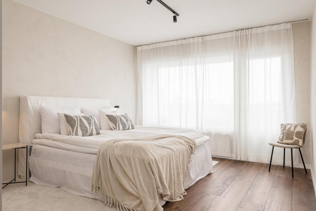a white bedroom with a large bed and a window at Borg Itsenäisyydenkatu, Centre Spacious 2-Room Apt, King Bed, Free Parking & Wifi in Pori