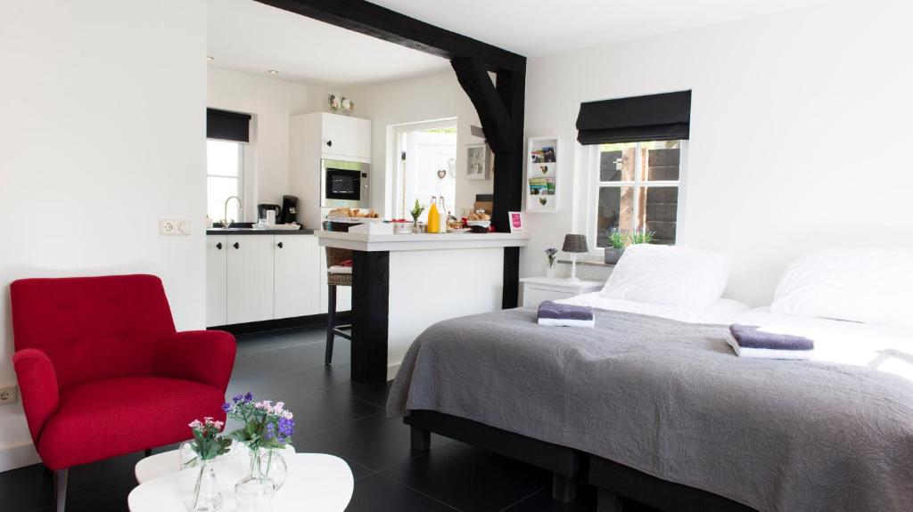 um quarto com uma cama e uma cadeira vermelha e uma cozinha em Bed and Breakfast De Reggestee em Hellendoorn