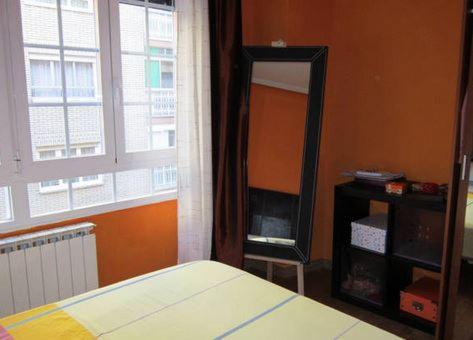 1 dormitorio con espejo, cama y ventana en Leon Apartamento Centro, en León