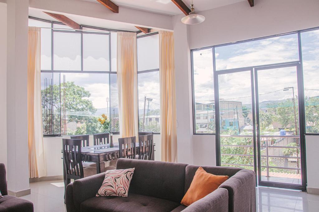 ein Wohnzimmer mit einer Couch und einem Tisch und Fenstern in der Unterkunft Charm & Confort - Tarapoto - Peru in Tarapoto