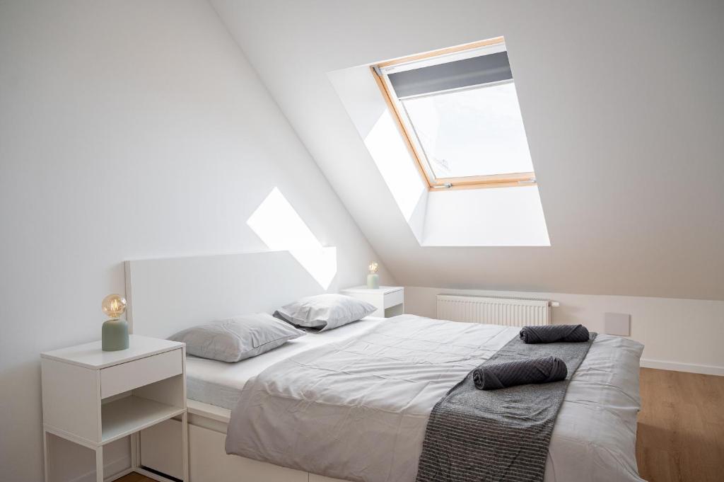 a white bedroom with a bed and a window at City Center Residence Free Parking in Bratislava