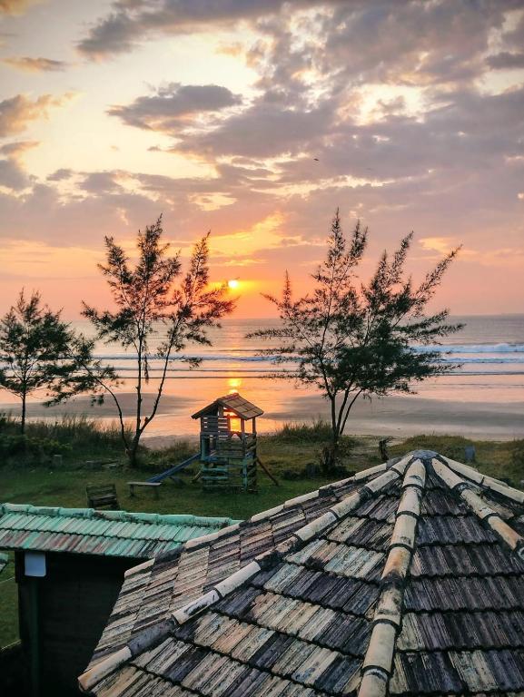 a view of a gazebo on the beach at sunset at Bangalô de frente pro mar in Imbituba