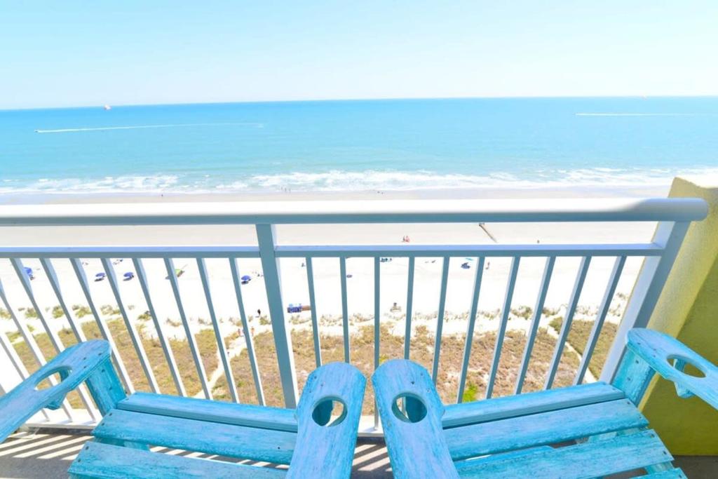 a blue bench sitting on a balcony overlooking the beach at Oceanfront TOP LOCATION MODERN RESORT Lazy River Huge Pool Oasis in Myrtle Beach
