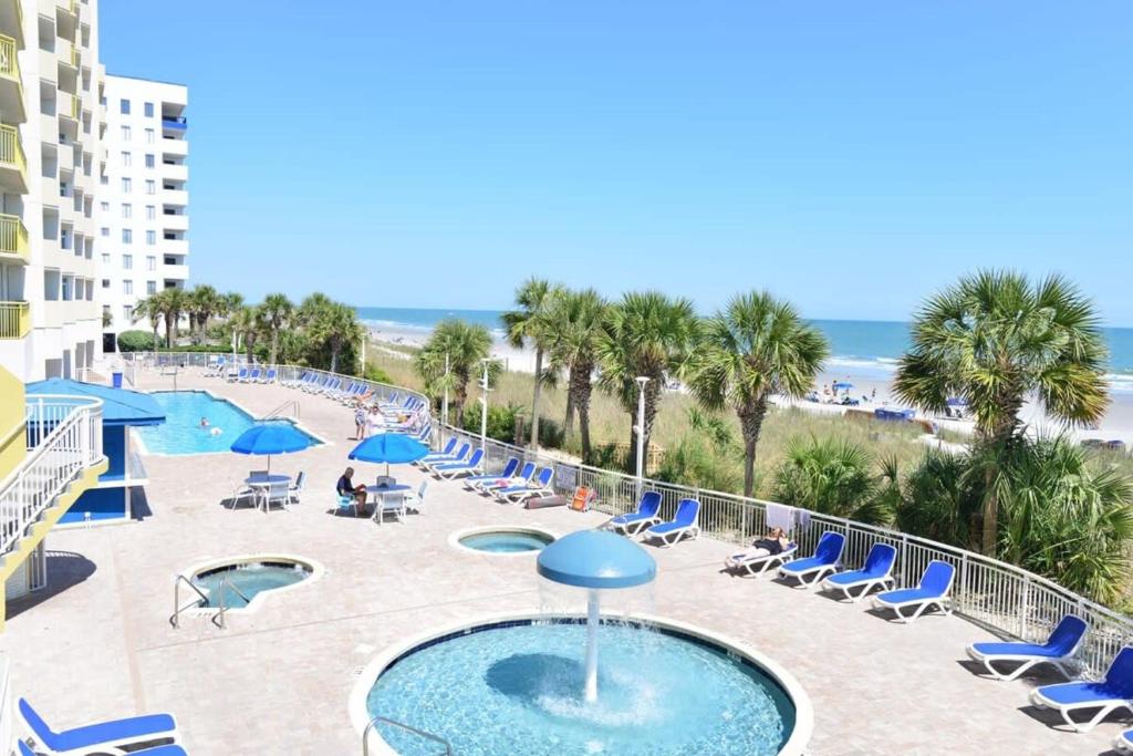 a pool with chairs and umbrellas and the beach at Oceanfront TOP LOCATION MODERN RESORT Lazy River Huge Pool Oasis in Myrtle Beach